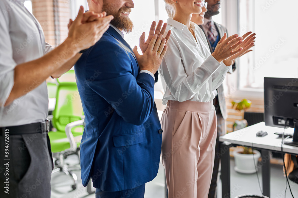 Obraz premium team of young diverse employees applauding, clapping hands, cheering mentor coach, in modern light office at corporate meeting, celebrating business achievement. cropped side view
