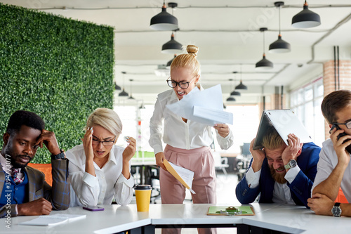 Obraz na plátně team of sad frustrated employees receiving rebuke by shouting female executive,