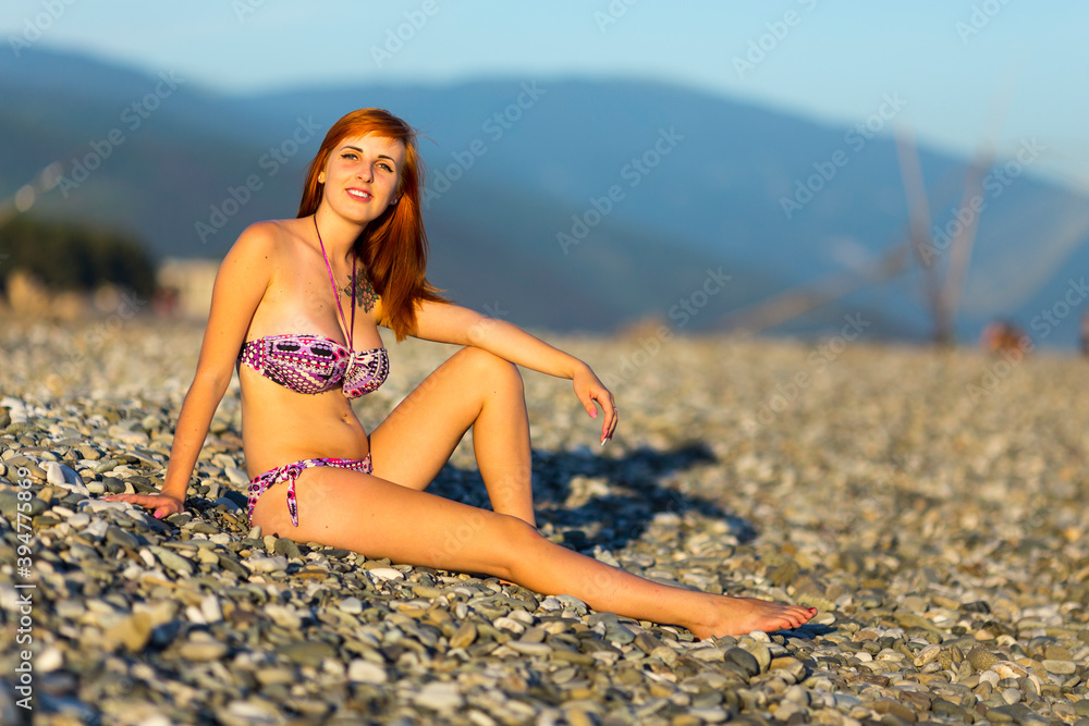 Beautiful young woman enjoing herself on pebble sunny beach