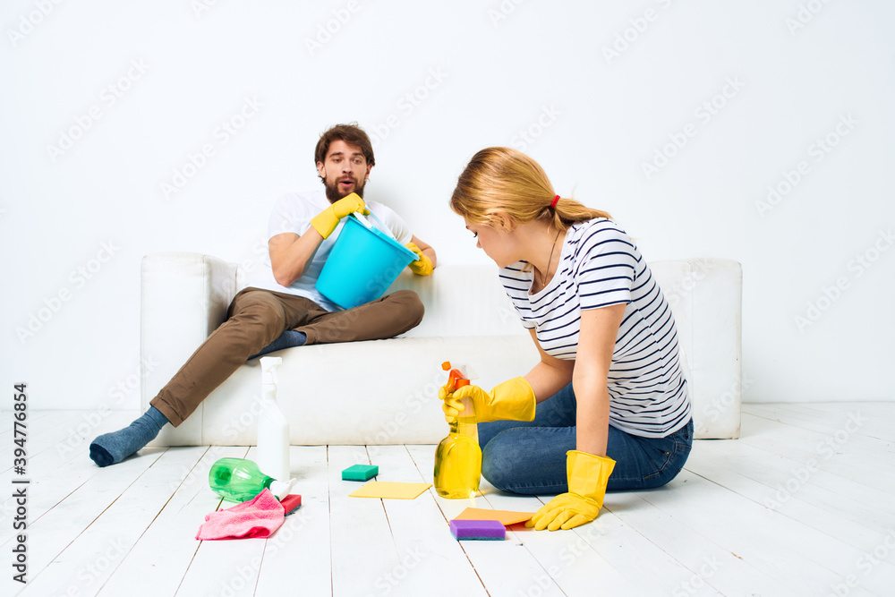 Young couple are doing cleaning together in the room light background 
