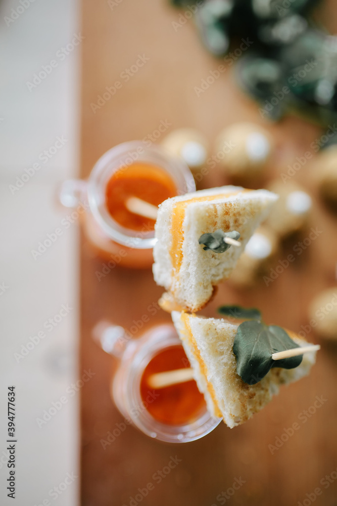 two mini grilled cheese sandwiches served on skewers in glass mugs of tomato soup two mini grilled cheese sandwiches served on skewers in glass mugs of tomato soup