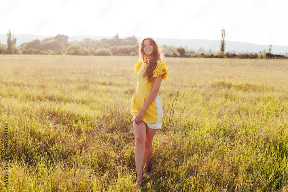 Beautiful woman in yellow dress walks on the field at sunset Stock ...
