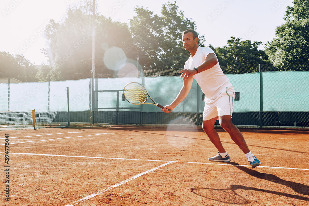 Fit man plays tennis on tennis field