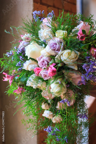 Beautiful wedding flowers with bright pinks and purples and a brick background by the window.