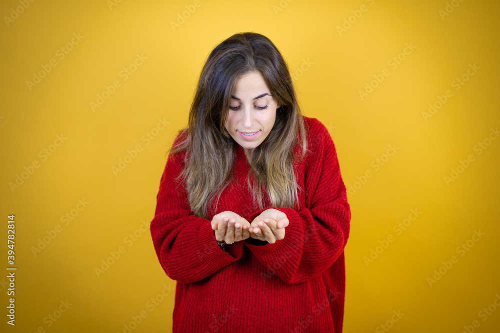 Young beautiful woman wearing red sweater over isolated yellow background Smiling with hands palms together receiving or giving gesture. Hold and protection Young beautiful woman wearing red sweater over isolated yellow background Smiling with hands palms together receiving or giving gesture. Hold and protection