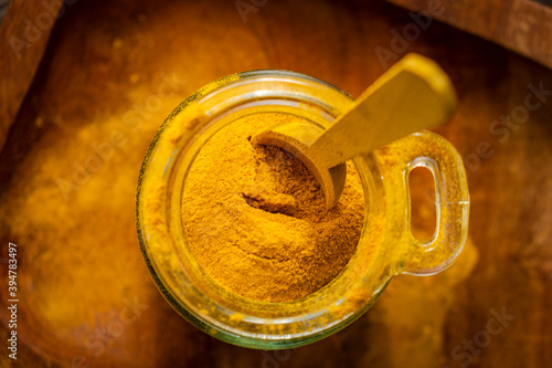 ground turmeric in a glass jar on wooden background photo