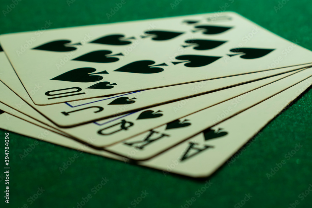 Playing cards suit of spades on a green table. Ace, karol, queen, jack, ten. Royal Flush. - obrazy, fototapety, plakaty 