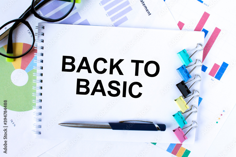 A Notepad with text Back To Basic with paper clips and a pen on it. Calculator and yellow stickers. A Notepad with text Back To Basic with paper clips and a pen on it. Calculator and yellow stickers.