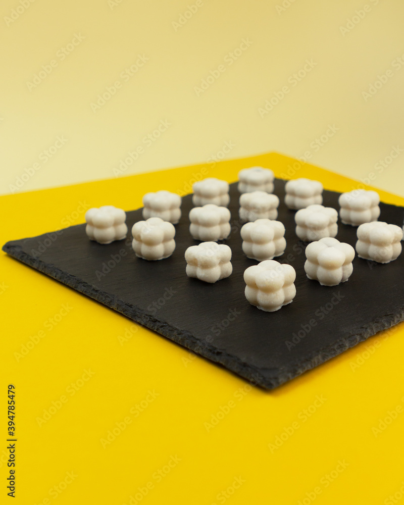 Homemade coconut manna sweets. Modern shape on a geometric yellow background. A fat bomb for the ketogenic diet. Homemade coconut manna sweets. Modern shape on a geometric yellow background. A fat bomb for the ketogenic diet.