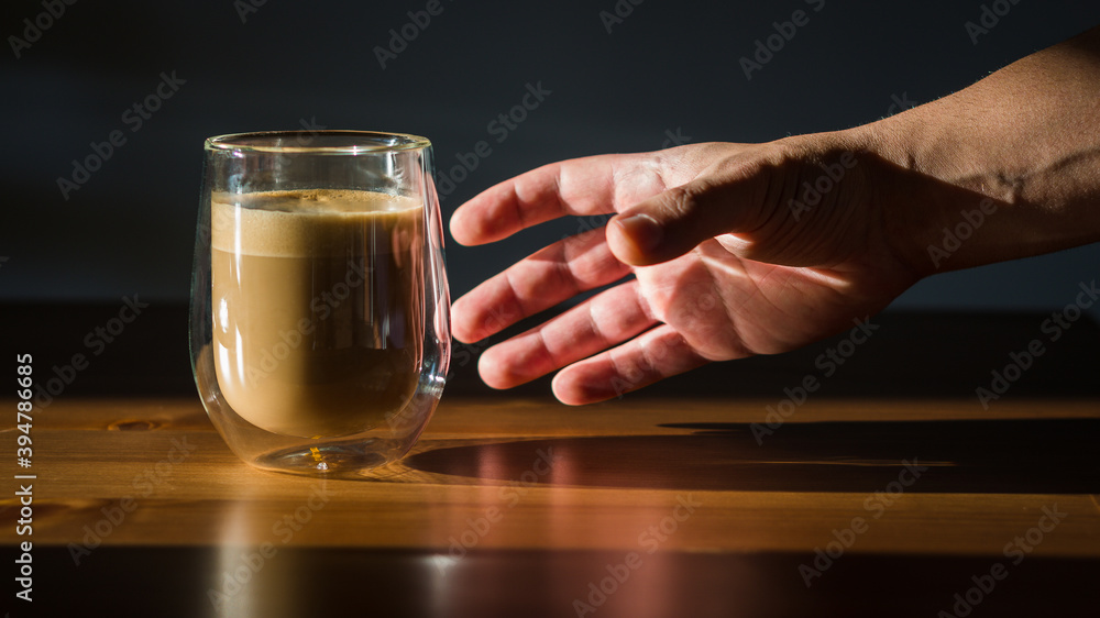 Male holds hand pglass cup with coffee on dark background Male holds hand pglass cup with coffee on dark background