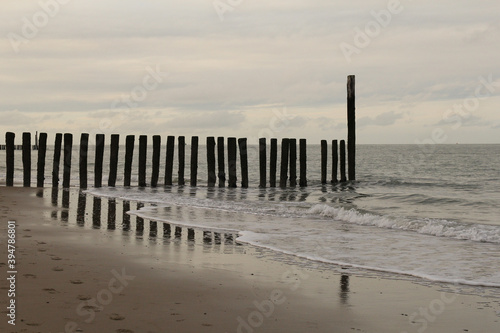 beautiful seascape in Breskens  zeeland  the netherlands  with reflection of the beach poles in the water of scheldt river in winter