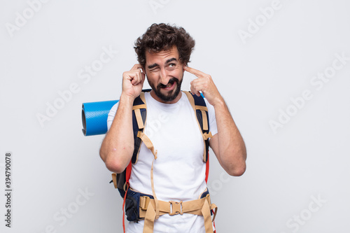 young man looking angry, stressed and annoyed, covering both ears to a deafening noise, sound or loud music photo