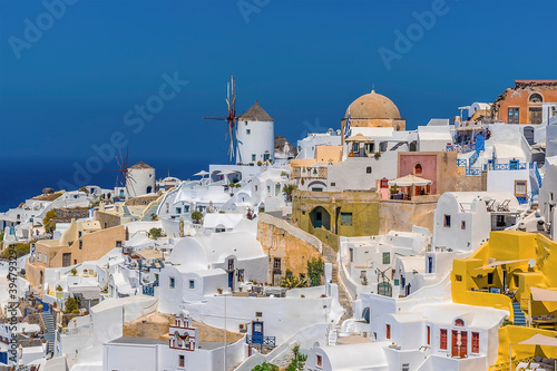 Traditional windmills and white buildings dominate the northern edge of the village of Oia, Santorini in summertime