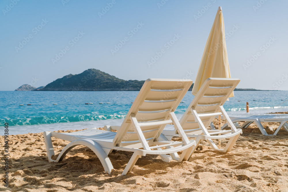 Two beach chairs and umbrella on the beautiful sand beach waiting for someone to come relax. Travel, holidays and resort concept. Two beach chairs and umbrella on the beautiful sand beach waiting for someone to come relax. Travel, holidays and resort concept.