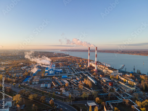 Factory chimneys producing smoke at sunrise, aerial view. Concept of air pollution, environment and ecology crisis, climate change, global warming.