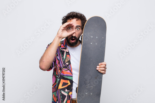 young man feeling shocked, amazed and surprised, holding glasses with astonished, disbelieving look photo