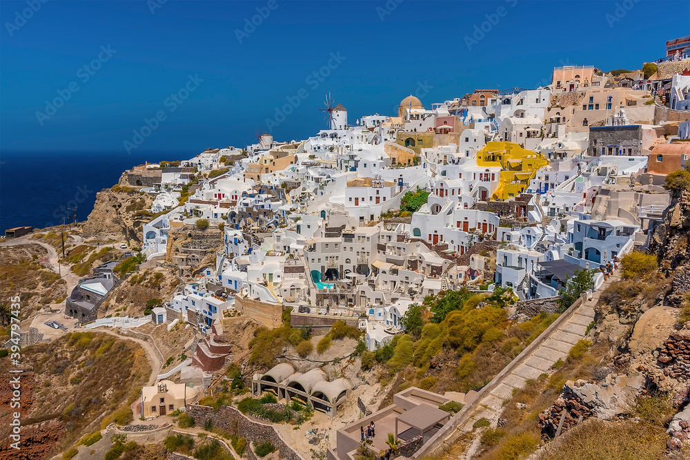 The white buildings of the village of Oia, Santorini tumble down the cliff towards Amoudi Bay in summertime