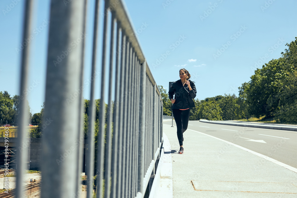 Fast female runner running on the bridge on a sunny day.