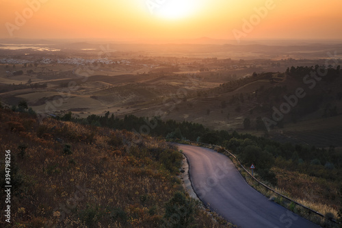 curved road in a rural setting at sunset with fog on the horizon