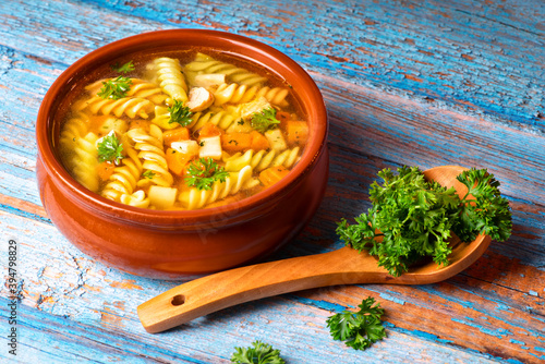 Pasta soup with vegetables on a blue wooden platter with parsley. photo