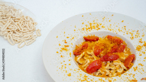 Fresh lorighittas semolina pasta with grated bottarga and cherry tomatoes