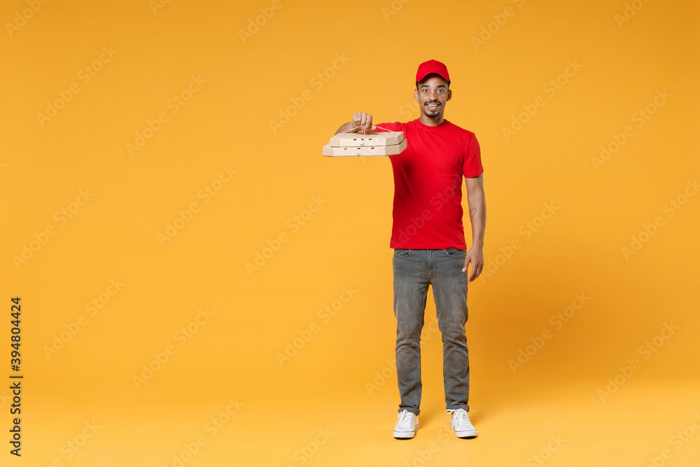 Full length delivery employee african man in red cap blank print t-shirt uniform work courier dealer service concept hold give food order pizza cardboard boxes isolated on yellow background studio Full length delivery employee african man in red cap blank print t-shirt uniform work courier dealer service concept hold give food order pizza cardboard boxes isolated on yellow background studio