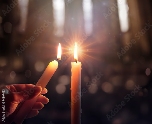 Canvas Print Defocused Hope Concept - Hand Igniting A Candle With Shining Flame And Blurry Li