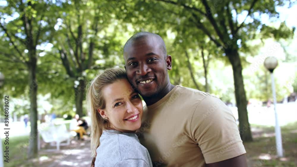 Multiracial couple hugging in public park. Multiracial couple hugging in public park.