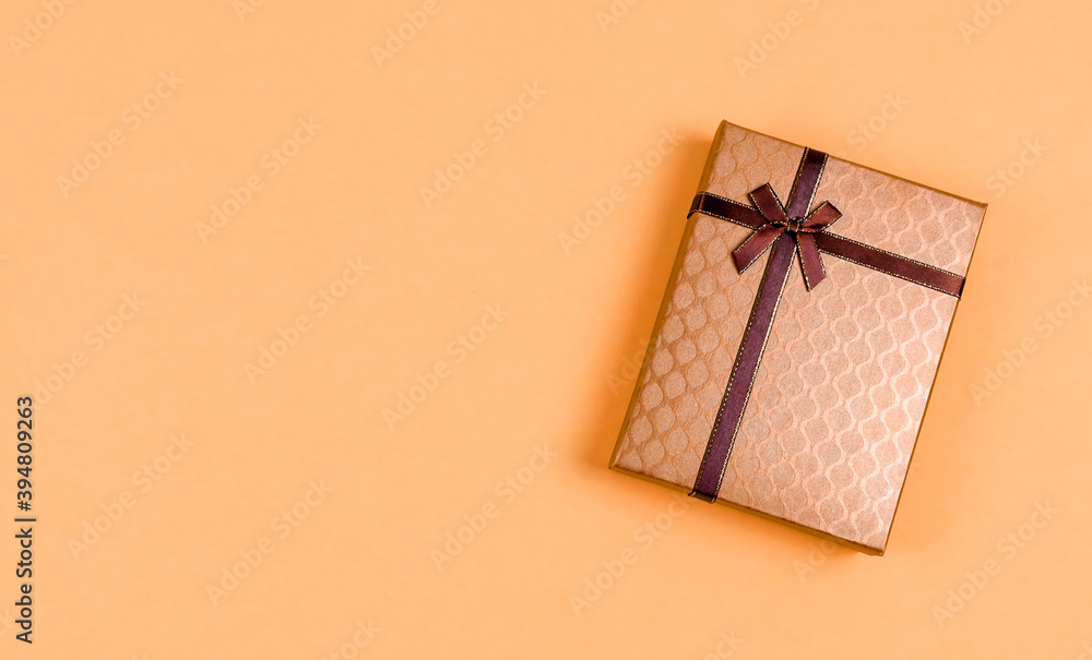 gift box with ribbon.
A gift box with a brown ribbon lies on the right against a champagne-colored background with a place for text on the left, a close-up top view. gift box with ribbon.
A gift box with a brown ribbon lies on the right against a champagne-colored background with a place for text on the left, a close-up top view.