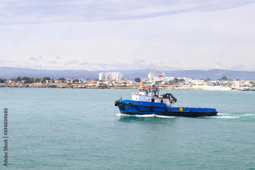 Boat in blue sea with blue sky and view of the beach on background, Vinaros, Valencia, Spain