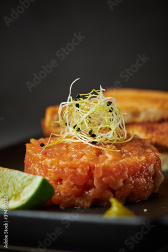 Detail of salmon tartare served with microgreens, lime, and toast, copy space