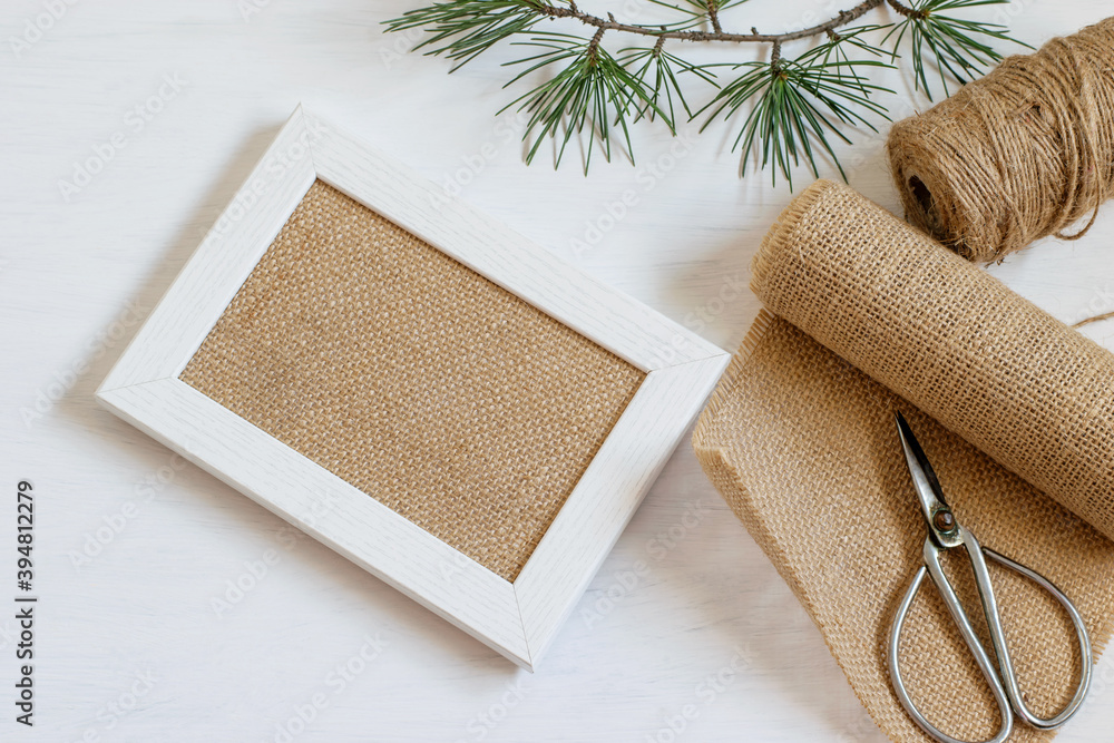 Handmade wooden picture frame with burlap in the center. Burlap cloth, rope and scissors for diy at home. Zero waste, plastic free life style. Mock up photo. Handmade wooden picture frame with burlap in the center. Burlap cloth, rope and scissors for diy at home. Zero waste, plastic free life style. Mock up photo.
