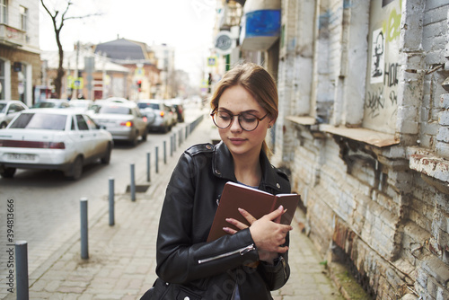 A woman walks down the street near an old building in a leather jacket model  © SHOTPRIME STUDIO