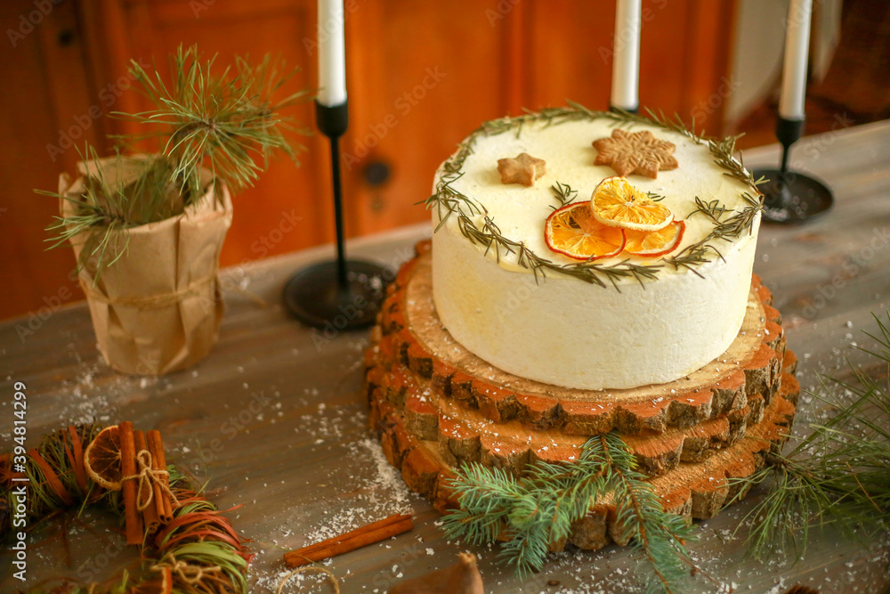 cake decorated with dried oranges and cookies in the form of snowflakes on a wooden table with Christmas decorations