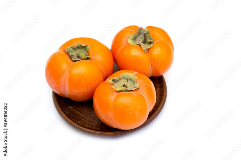 Persimmon. Vitamins in winter, Three ripe persimmons on a plate Persimmon. Vitamins in winter, Three ripe persimmons on a plate