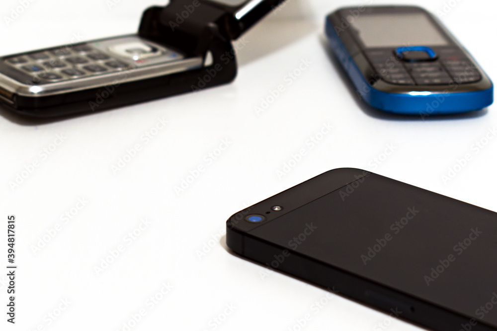 modern smartphone on blurred background of old push-button phones with focus in the center of image modern smartphone on blurred background of old push-button phones with focus in the center of image