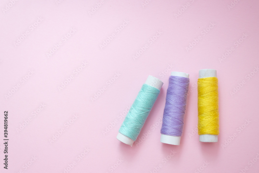 Colored sewing thread on a pink background Colored sewing thread on a pink background