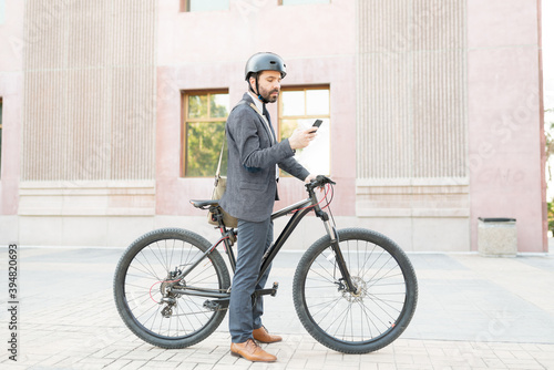 Side view of a businessman using his smartphone before starting to ride a bicycle