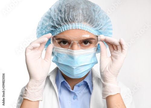 Doctor with medical gloves, mask, cap and protective goggles on white background