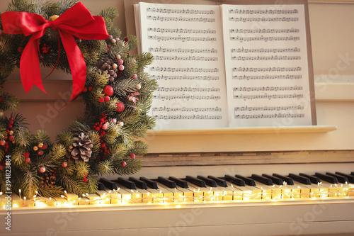 Photography White piano with decorative wreath and note sheets closeup