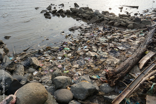 Large amounts of plastic and wood waste on the beach, polluting the marine ecosystem.