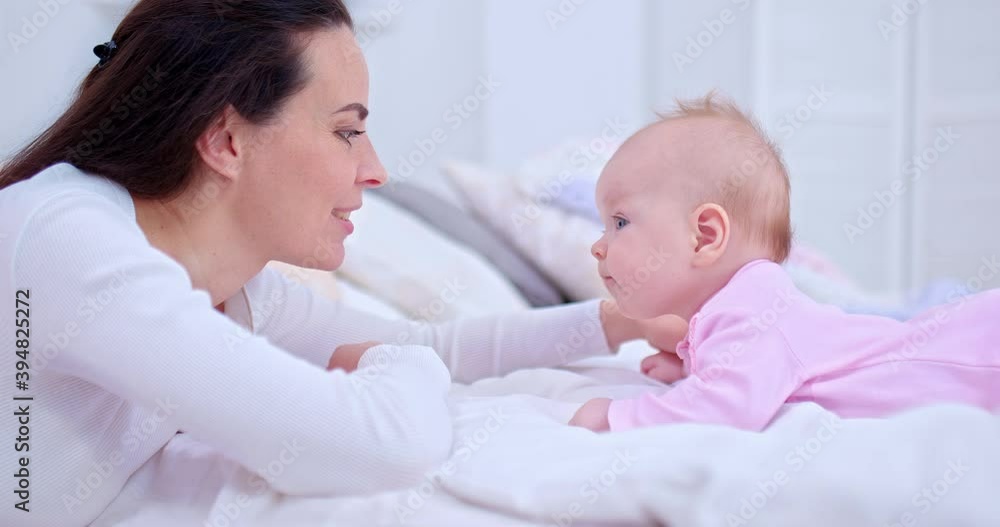 Portrait, a young beautiful mother is talking with her baby daughter, touching the baby on the face and smiling. Communication between mother and baby, family values. 4k, ProRes Portrait, a young beautiful mother is talking with her baby daughter, touching the baby on the face and smiling. Communication between mother and baby, family values. 4k, ProRes