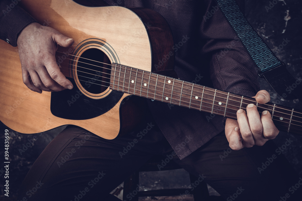Mature musician plays acoustic guitar emotional studio portrait.