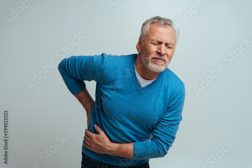 Handsome senior  isolated on grey background. Old man feeling pain. Concept about the third age and seniority