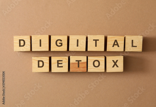 Wooden cubes with phrase DIGITAL DETOX on brown background, flat lay