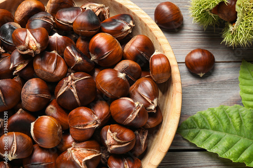 Delicious roasted edible chestnuts on brown wooden table, flat lay