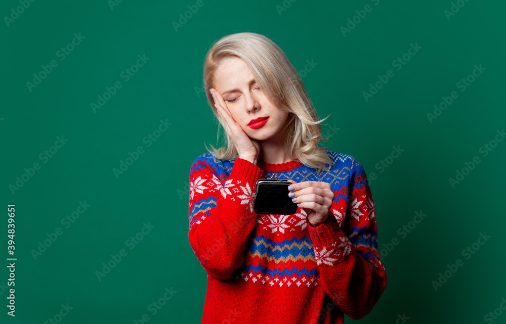Beautiful woman in Christmas sweater with empty purse on green background Beautiful woman in Christmas sweater with empty purse on green background