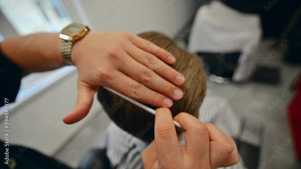 Barber quickly makes the client's hair styling with a comb and hands. Barber quickly makes the client's hair styling with a comb and hands.