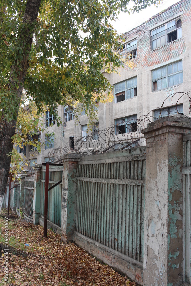 destroyed abandoned building broken Windows with broken glass on the facade behind the fence destroyed abandoned building broken Windows with broken glass on the facade behind the fence