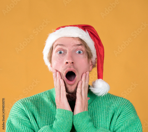 Young handsome man wearing santa claus hat. Funny face. Male portrait. Christmas time. Happy New Years. photo